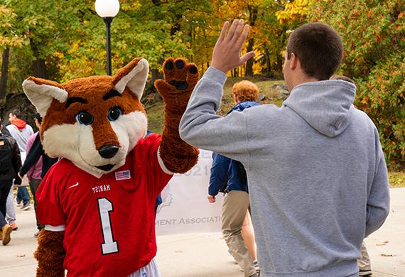 An image of a Marist student hi fiving Frankie the Fox. 